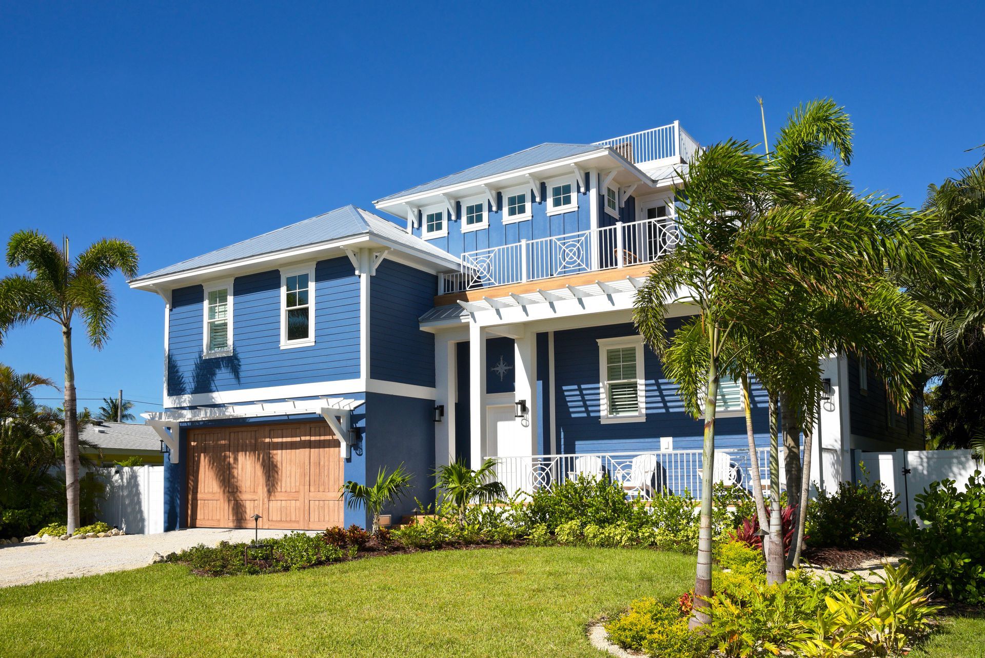 A large blue and white house with a lush green yard