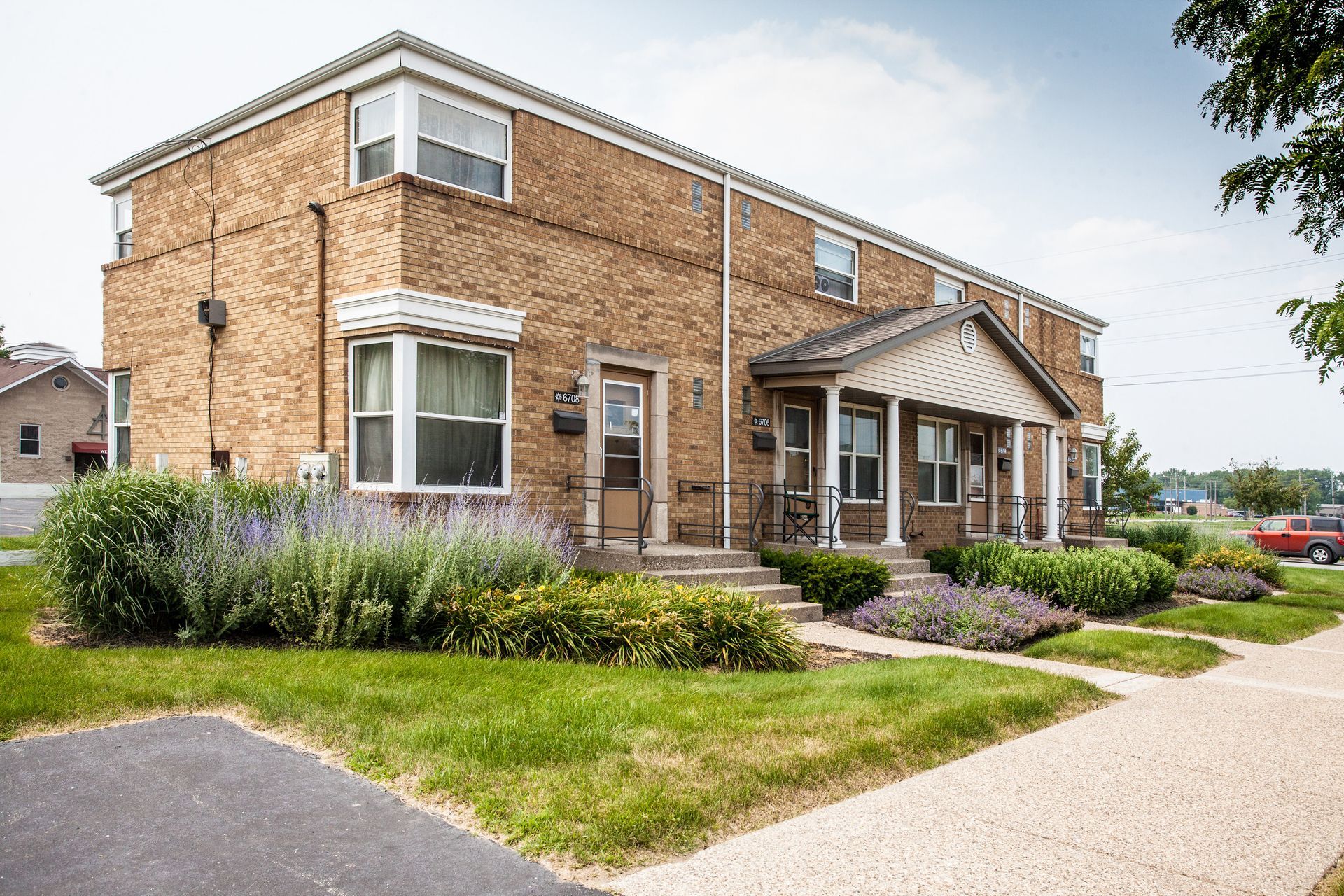Two-story brick building with multiple entrances, small front yards, and a sidewalk.
