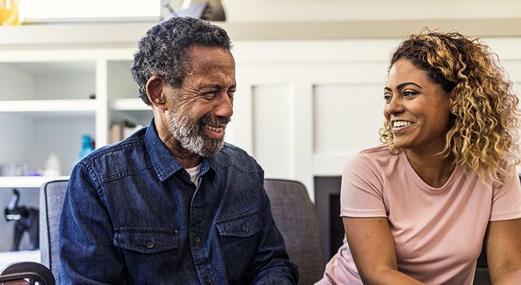A man and a woman are sitting on a couch talking to each other.
