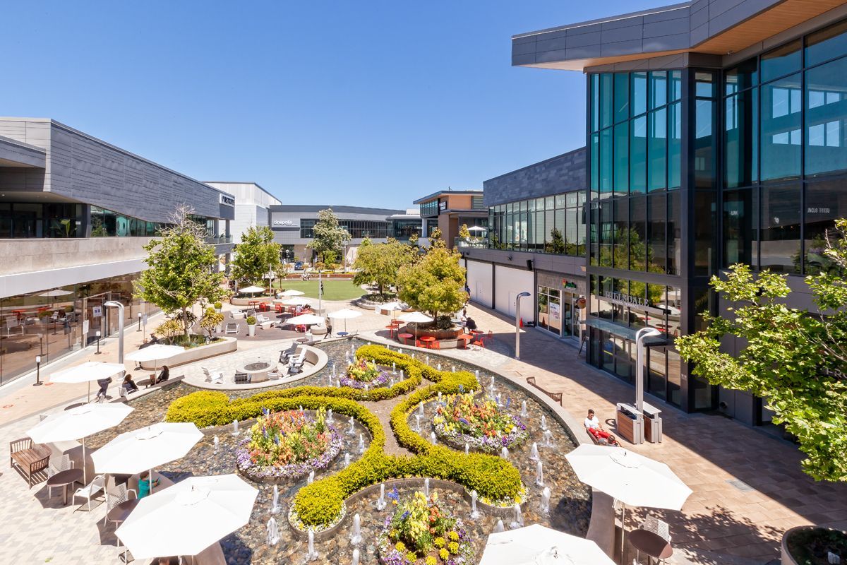 An aerial view of a shopping mall with a fountain and umbrellas.