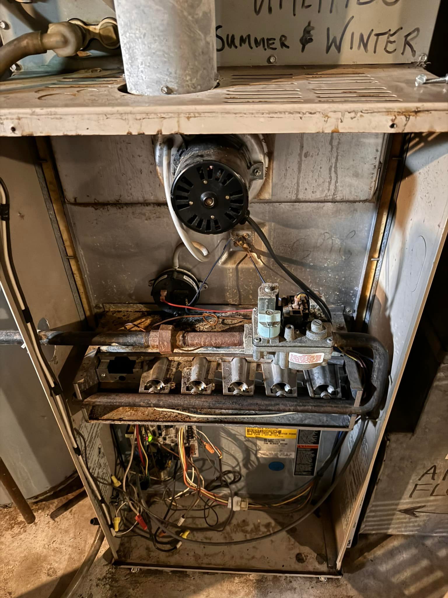 The inside of a dirty heater with a sign that says summer and winter on it.