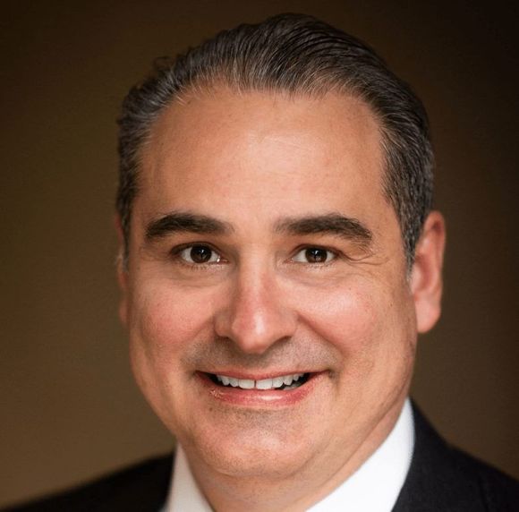 A man in a suit and tie is smiling for the camera.