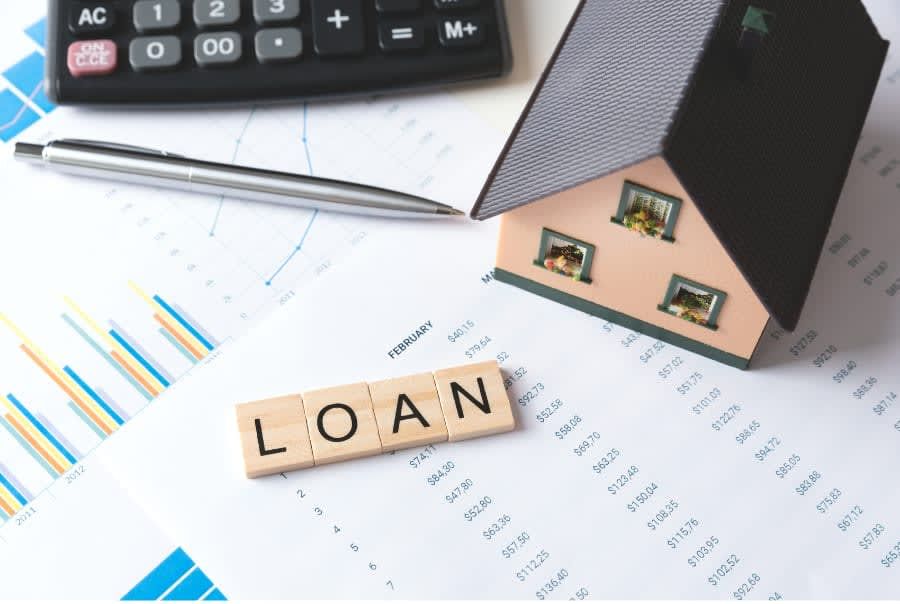 The word loan is written on wooden tiles next to a model house and a calculator.