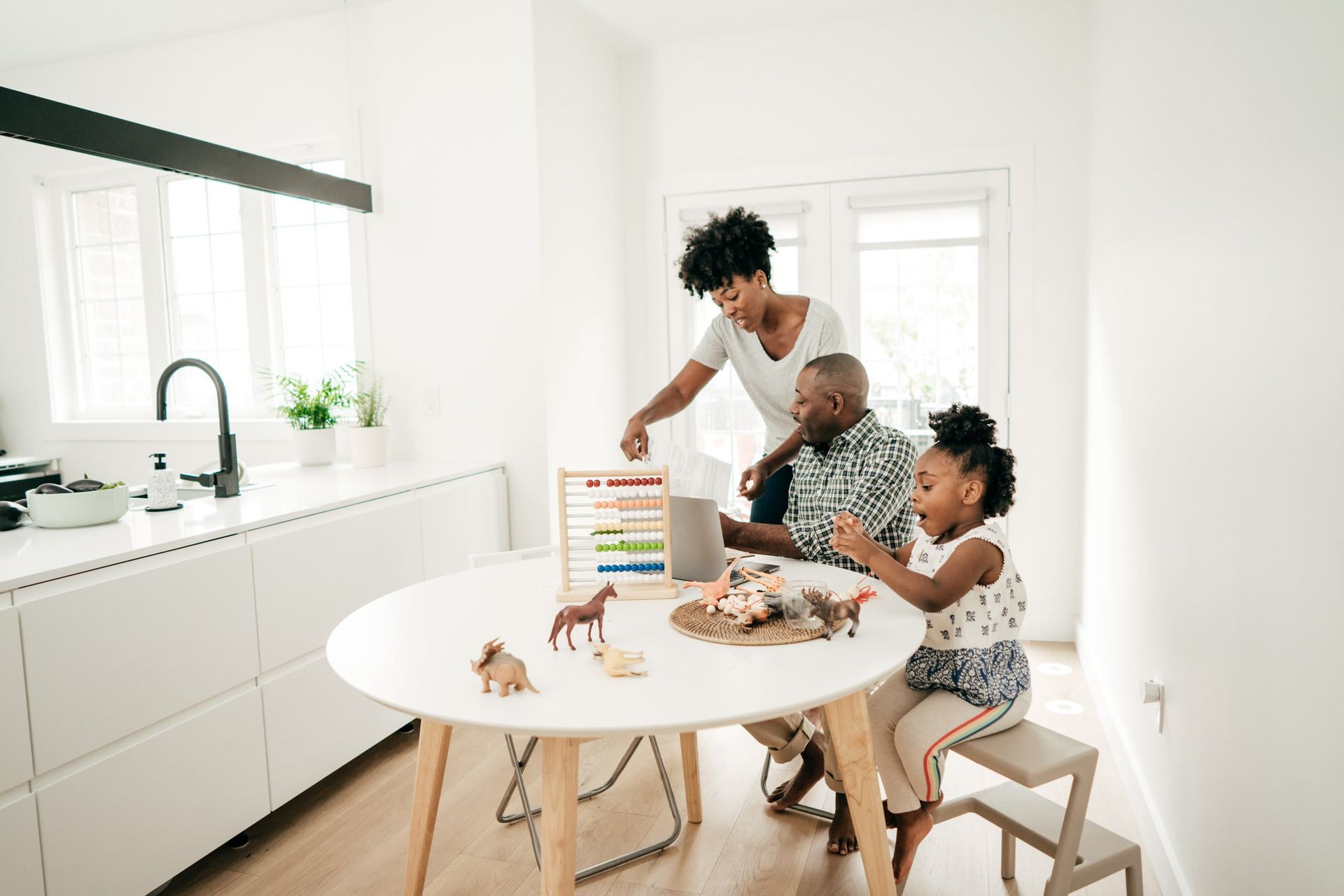 A family is playing with toys at a table in a kitchen.
