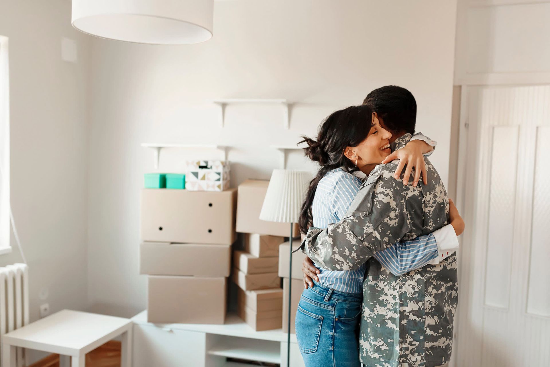 A man in a military uniform is hugging a woman in a living room.