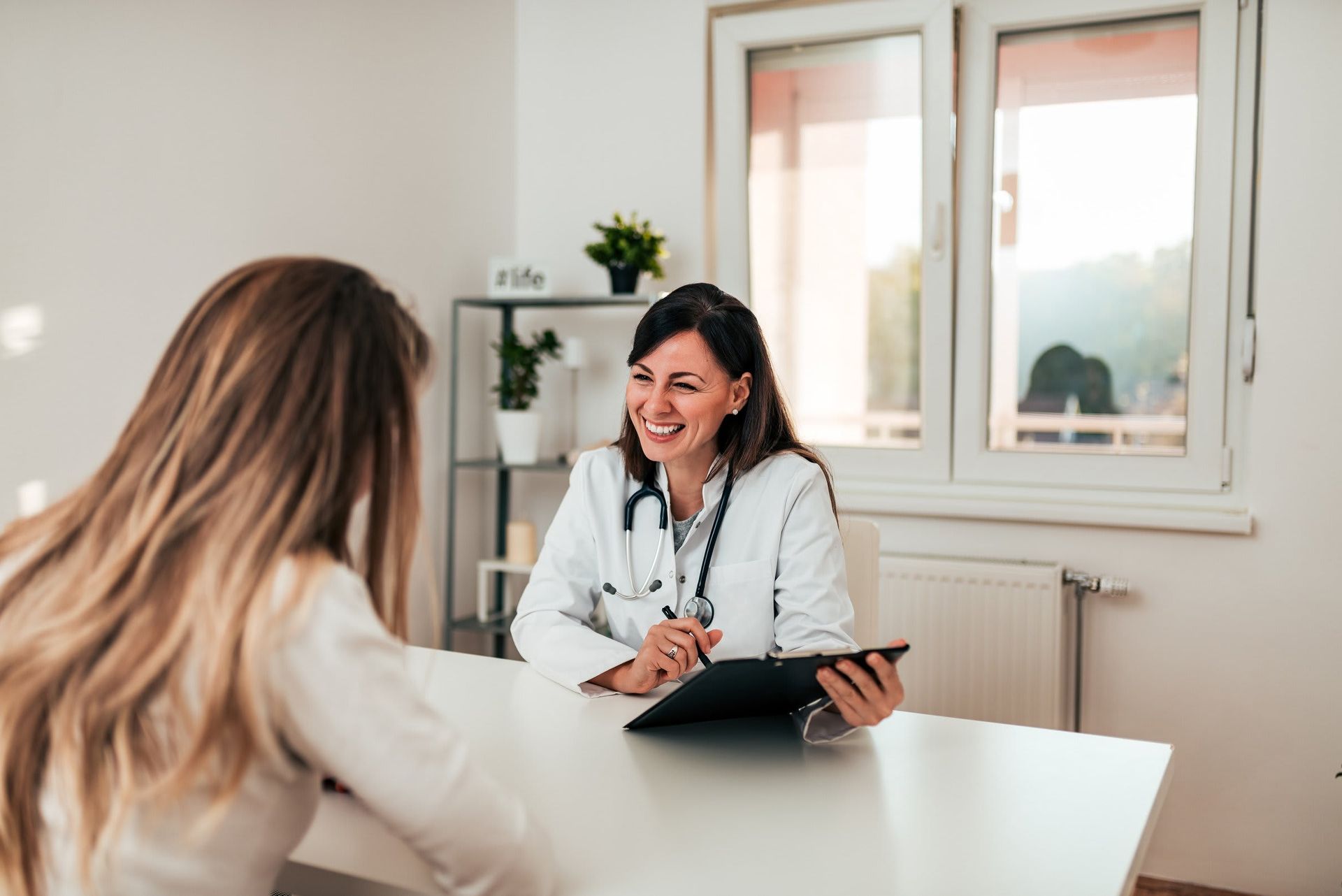 A woman is sitting at a table talking to a doctor.