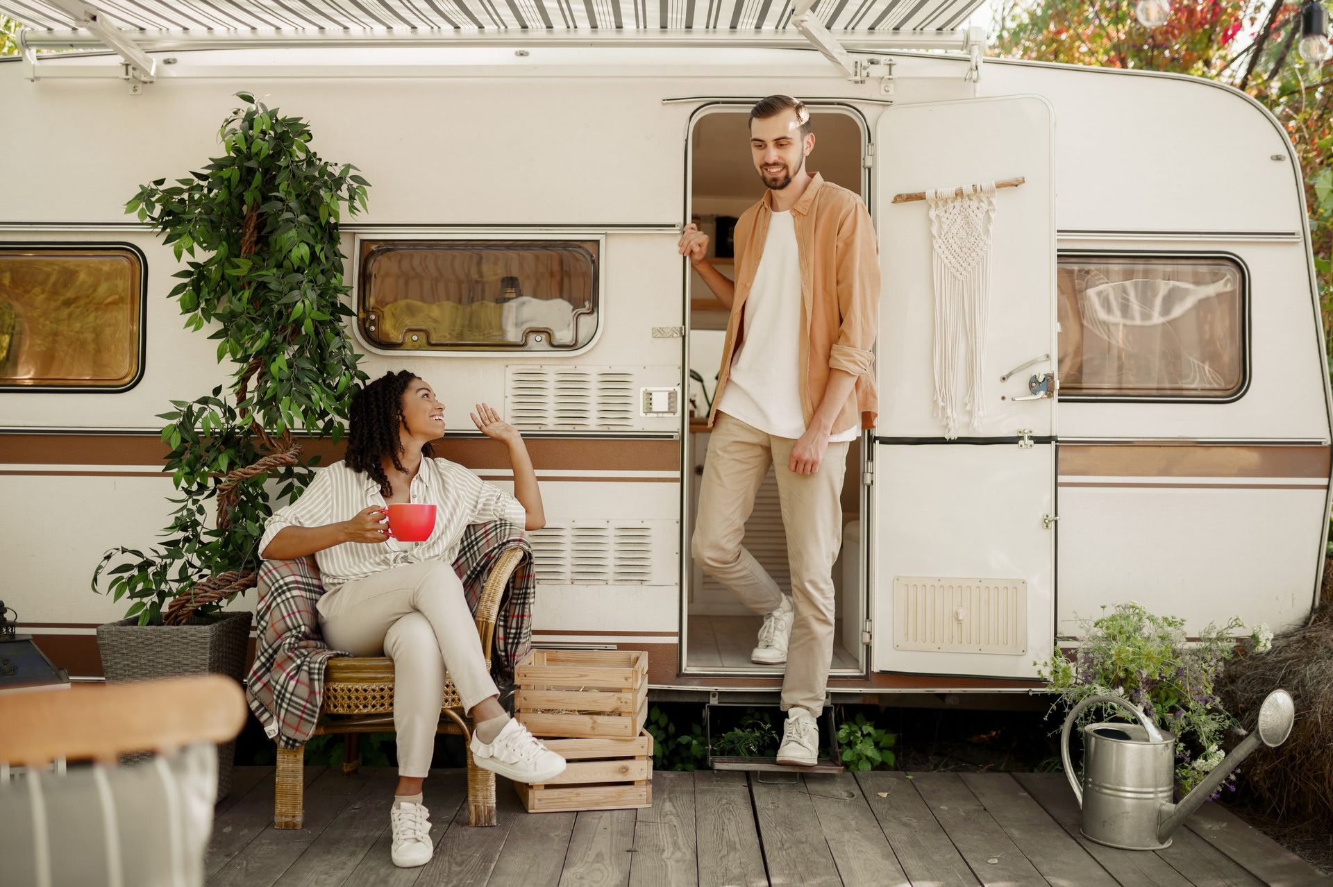 A man and a woman are standing in front of a trailer.
