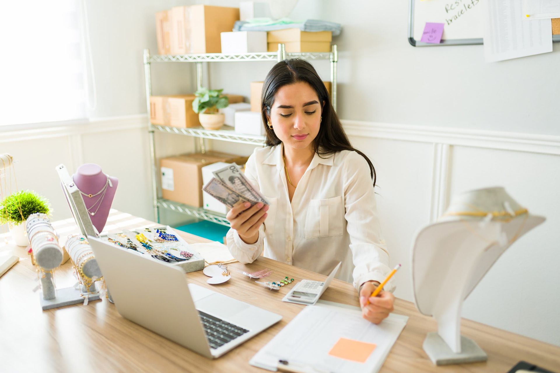 A woman is sitting at a desk holding a bunch of money.
