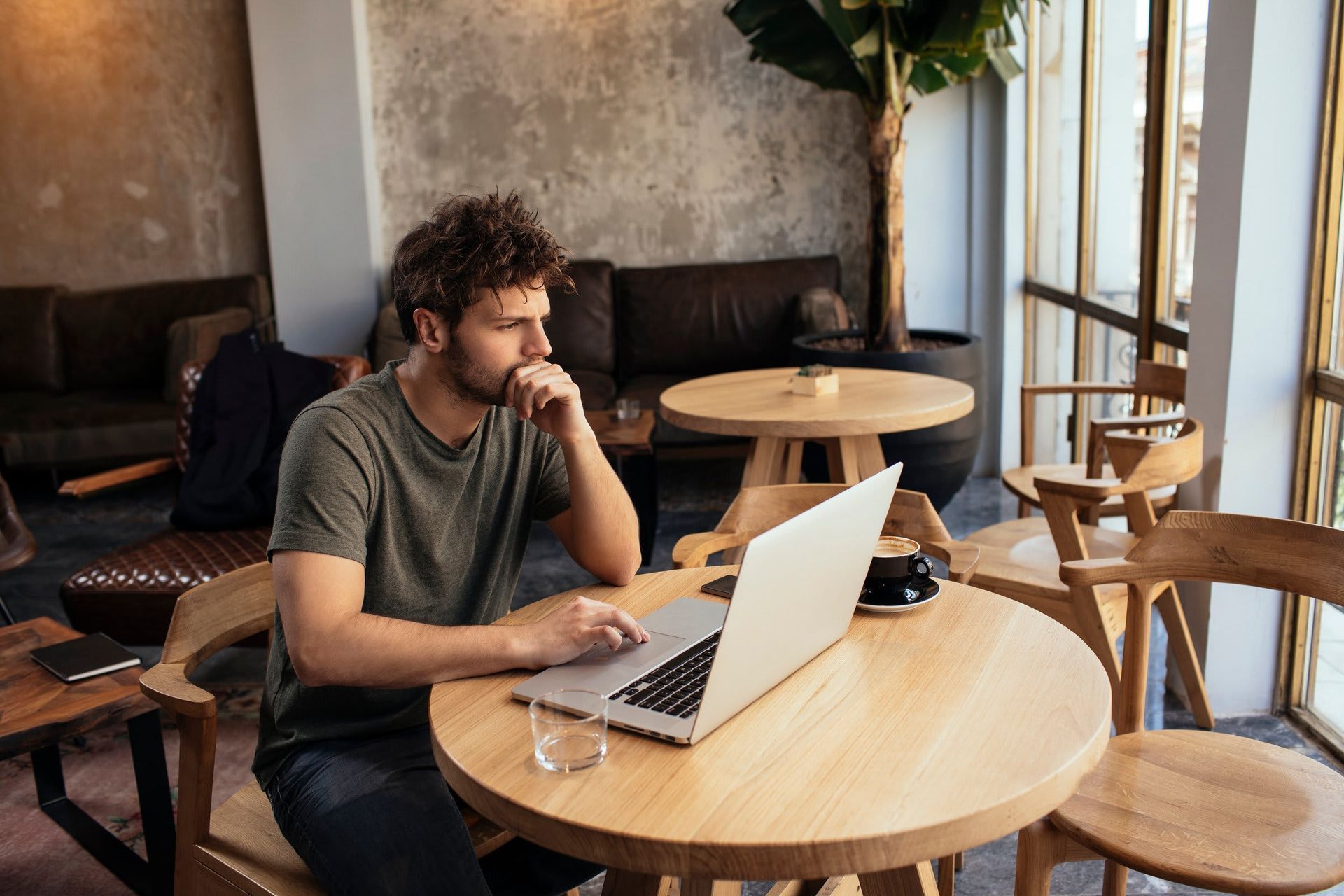 A man is sitting at a table using a laptop computer.