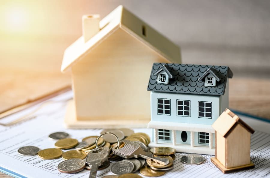 A model house sitting on top of a pile of coins.