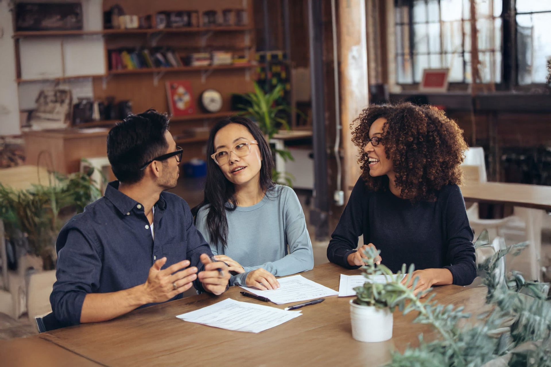 A group of people are sitting at a table talking to each other.