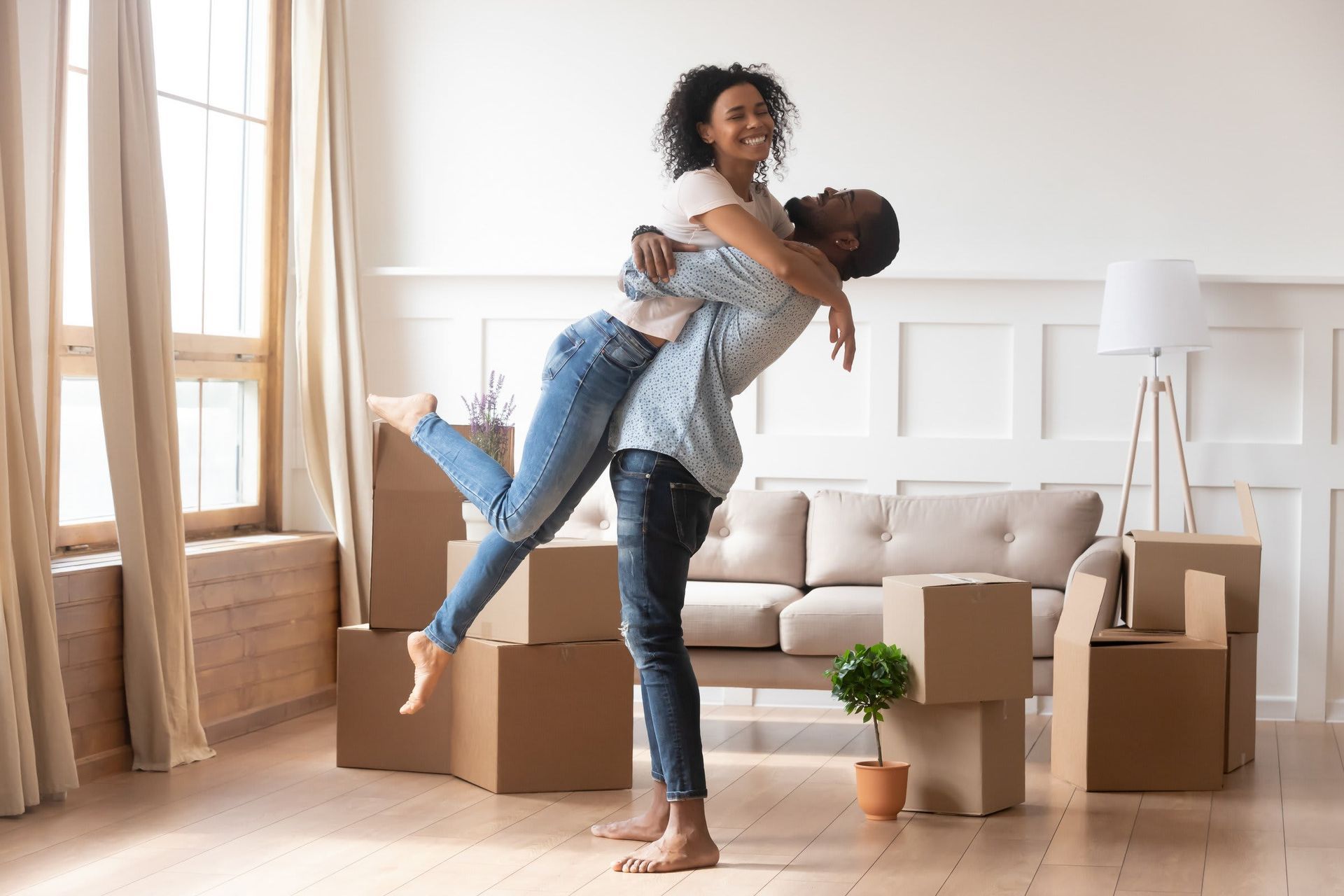 A man is holding a woman in his arms in a living room.