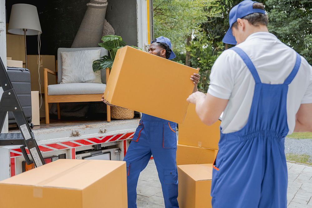 Two men movers worker in blue uniform unloading cardboard box into the truck. Professional delivery 