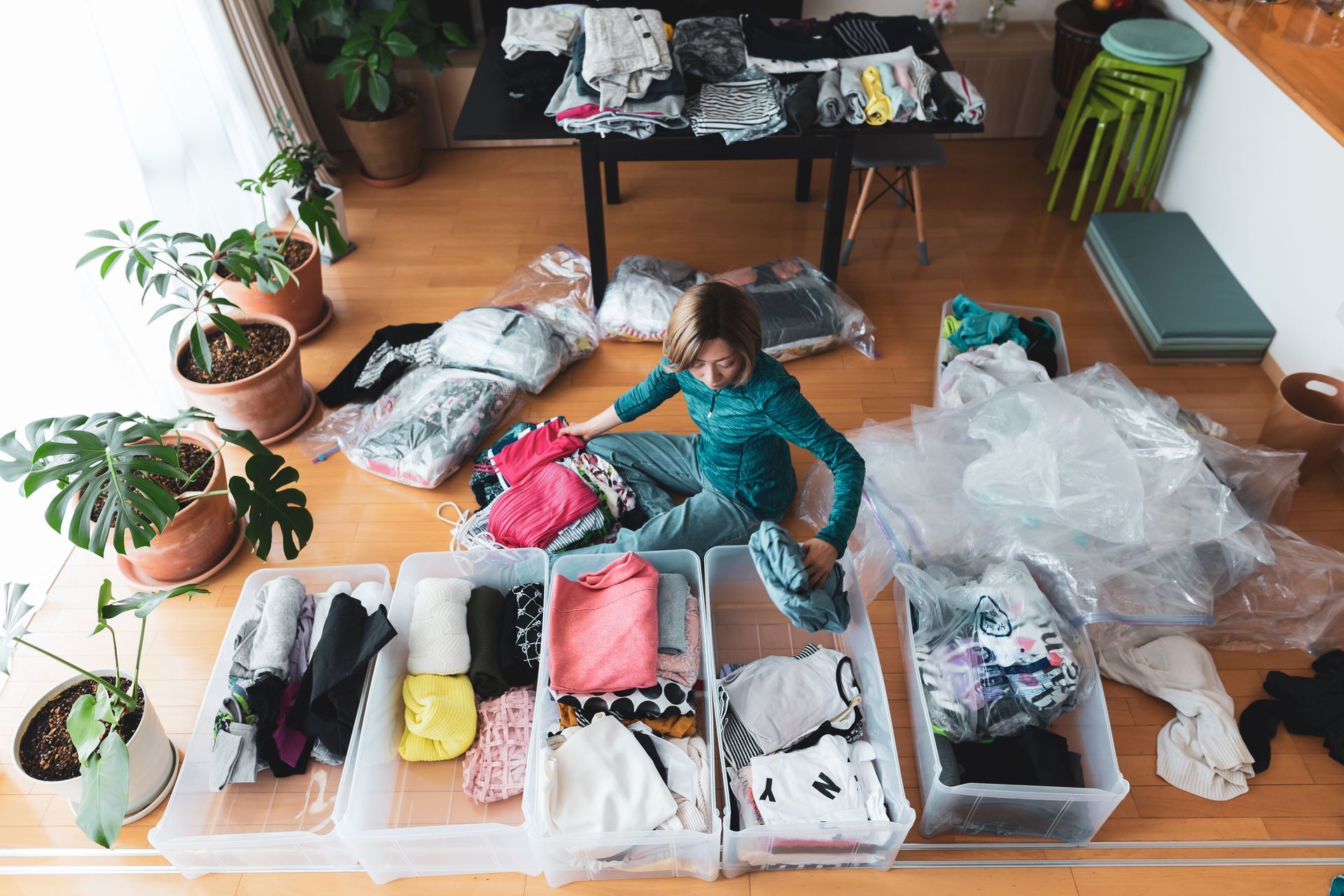 A woman is decluttering and organizing her clothes before residential moving services.