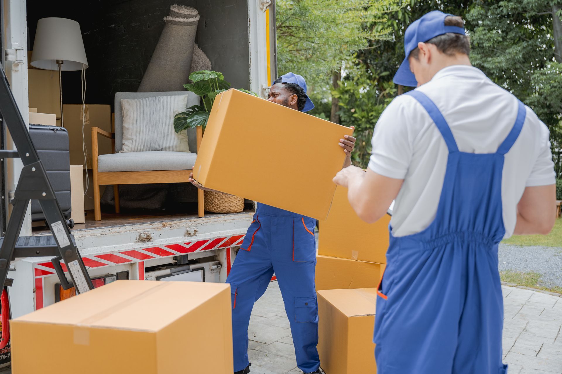 Two movers unload boxes from a truck, highlighting professional residential movers at work.