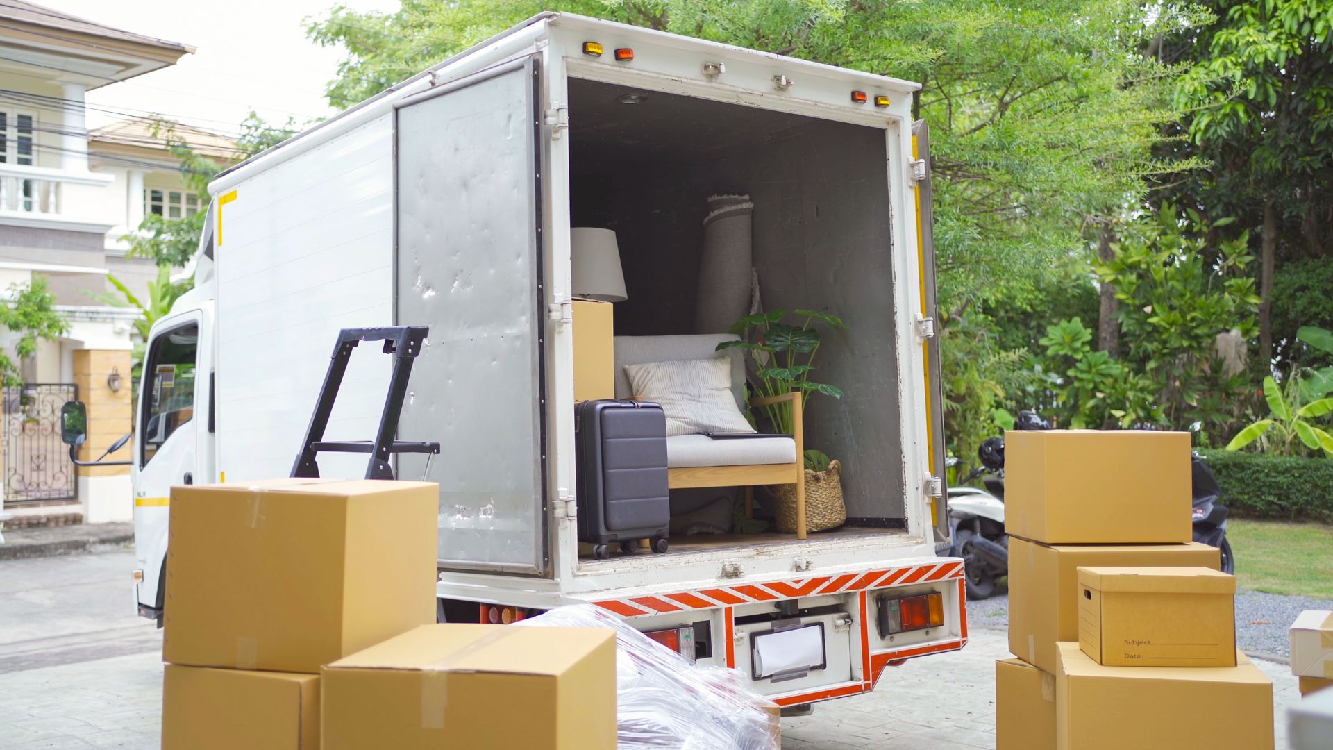 A truck outside a house full of furniture and boxes, showcasing residential moving services.