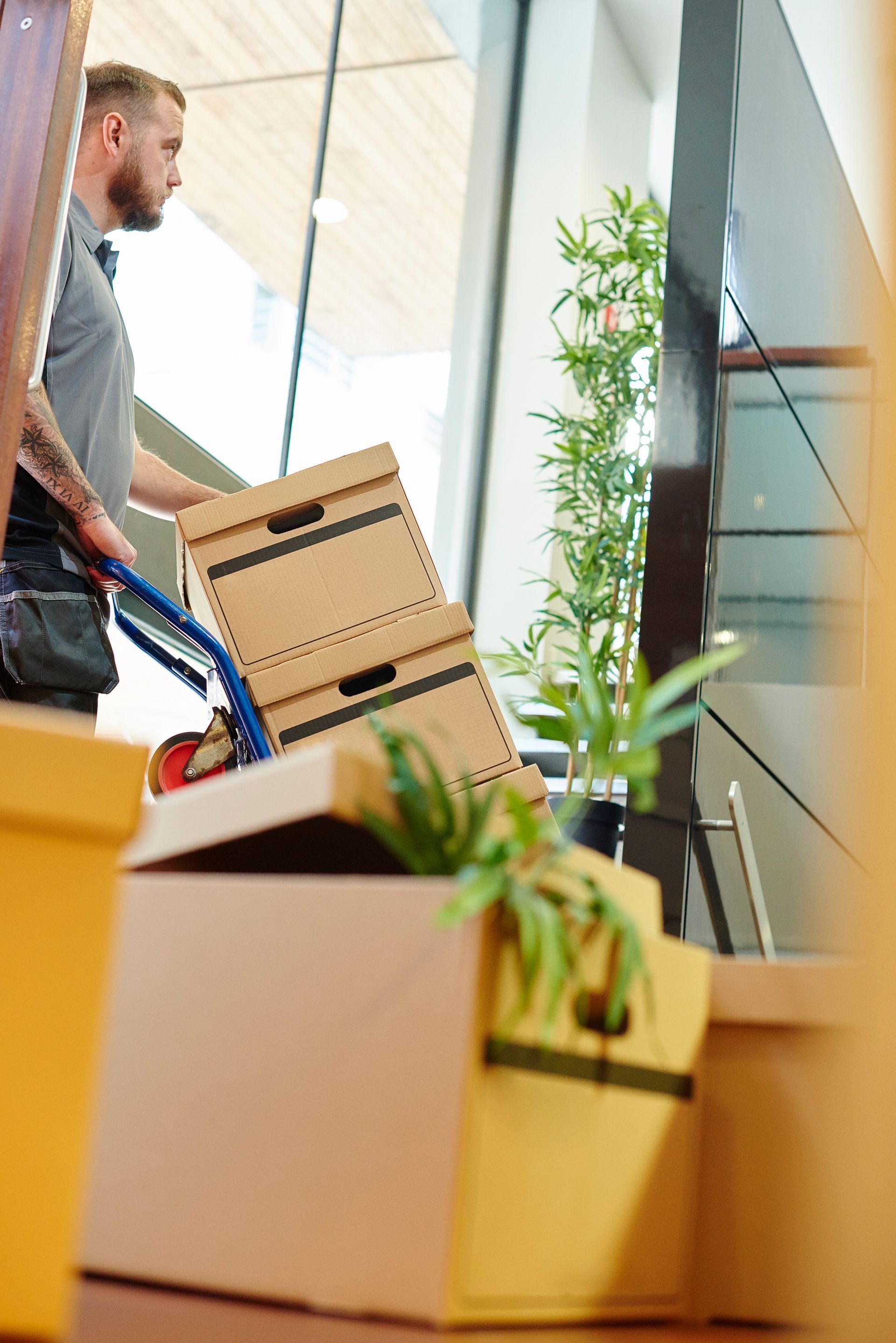 A man pushes a trolley of office boxes through the door of a modern office during a move.