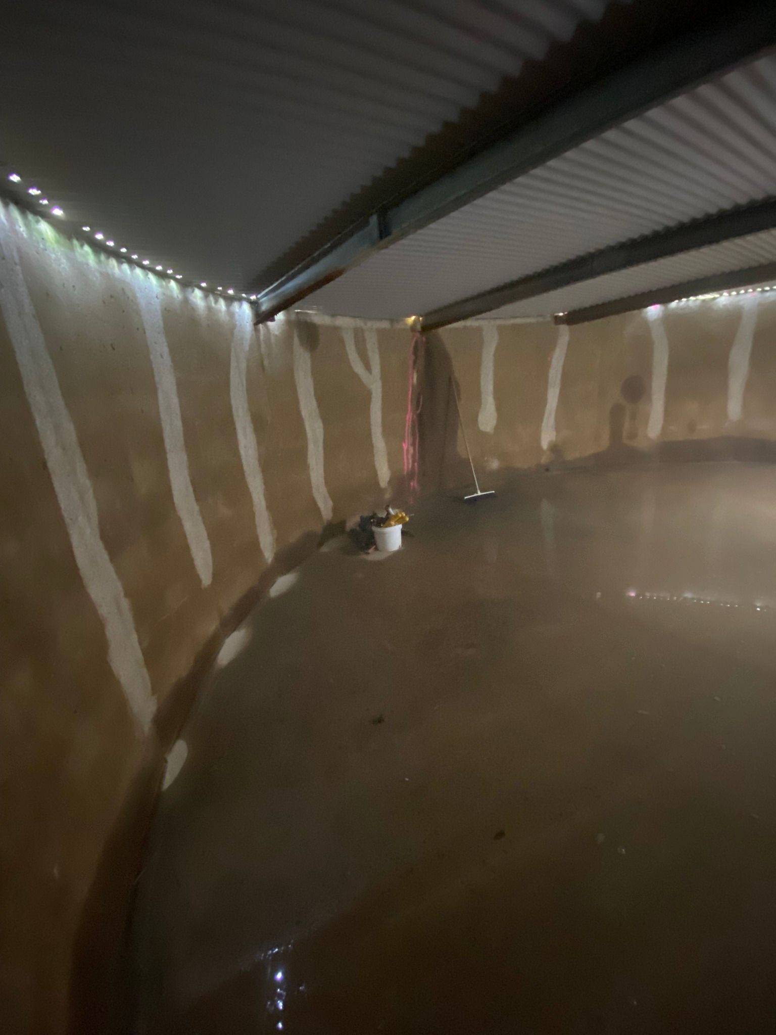 Interior view of a dark, flooded room with tan walls, white stripes, and string lights.