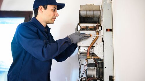 A man is working on a boiler in a room.