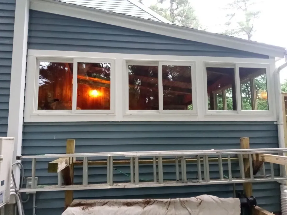 A blue house with white windows and a ladder on the side
