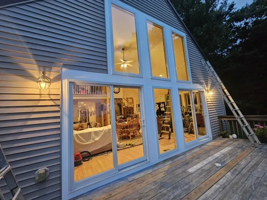 A house with a lot of windows and a potted plant on the deck.