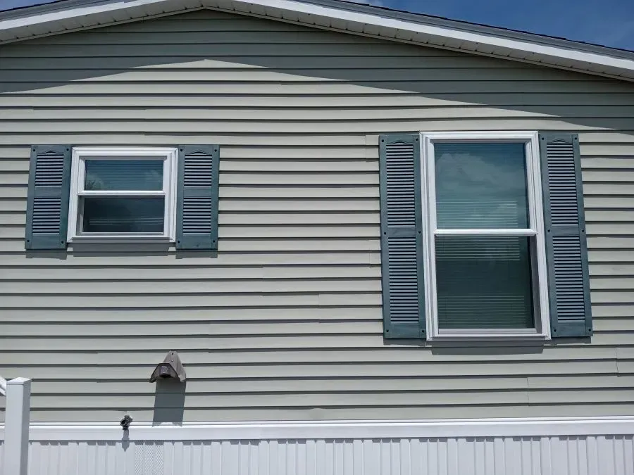 A house with shutters on the windows and a white fence