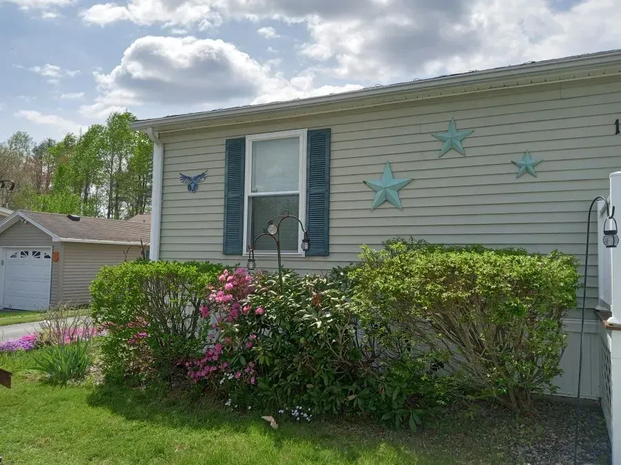 A mobile home with blue shutters and flowers in front of it.