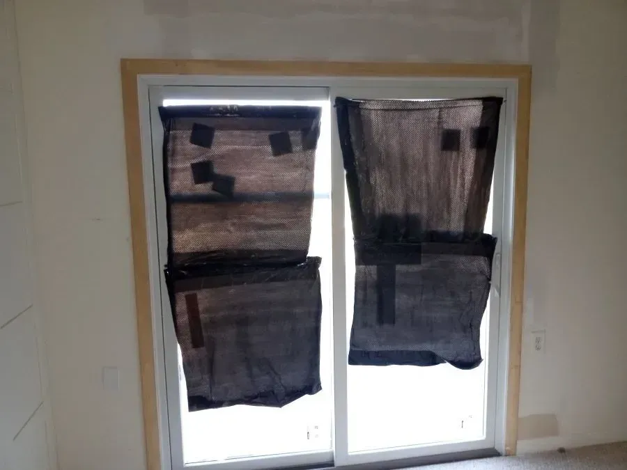 A sliding glass door is covered in black tarps