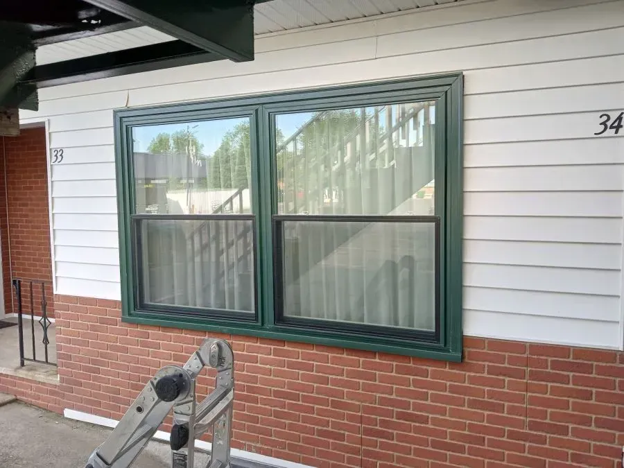 A ladder is sitting on the side of a house next to a window.