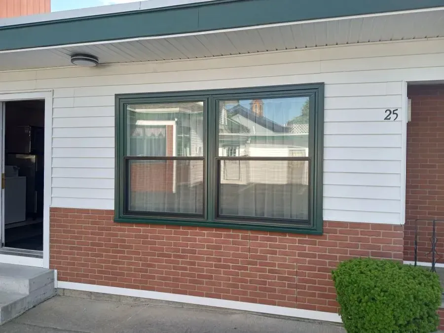 A brick house with a white siding and a green window.