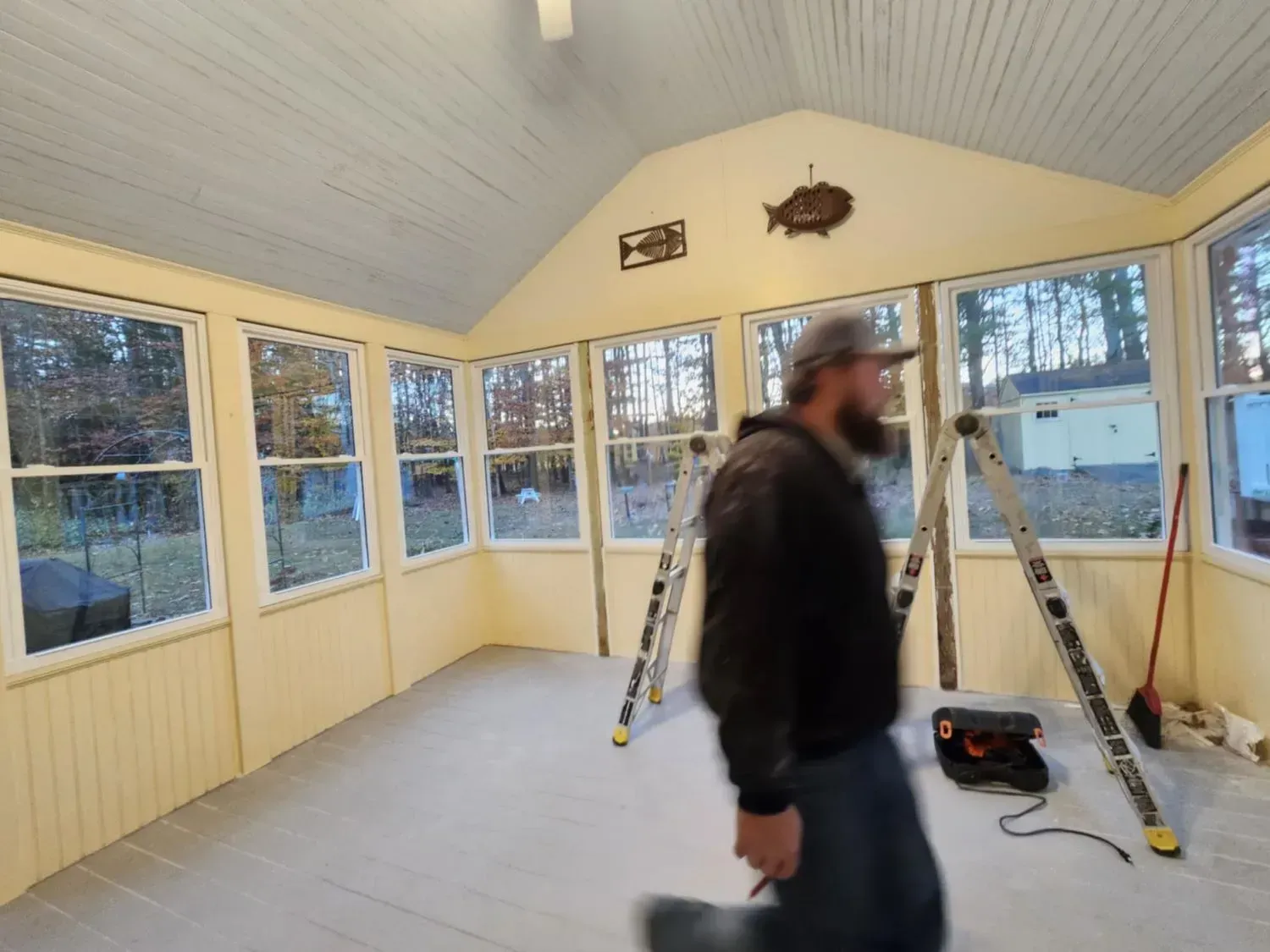 A man is standing in a room with a lot of windows and a ladder.