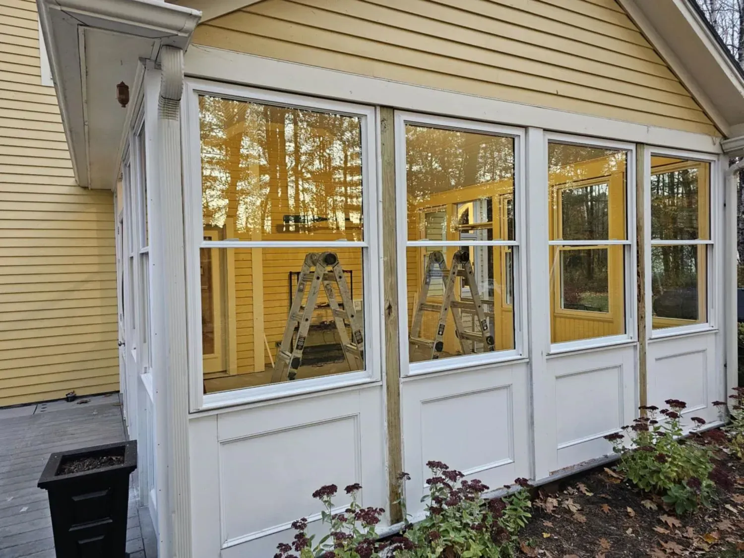 A yellow house with a white porch and lots of windows.