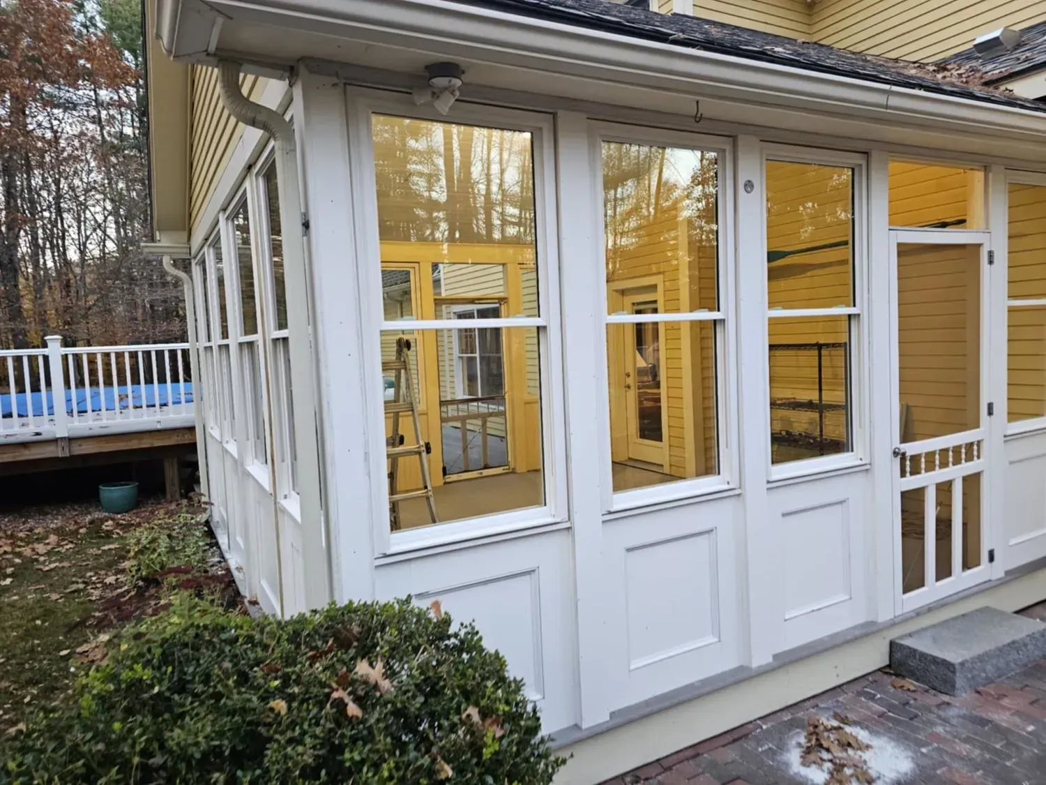 A screened in porch with a lot of windows and doors on a house.
