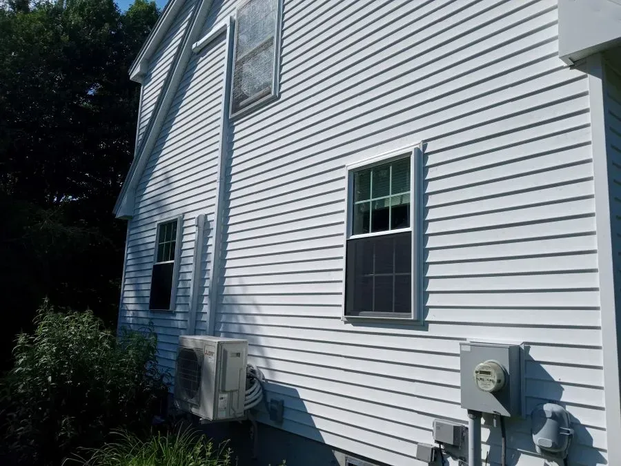 White house exterior with siding, windows, an AC unit, and electrical meter.