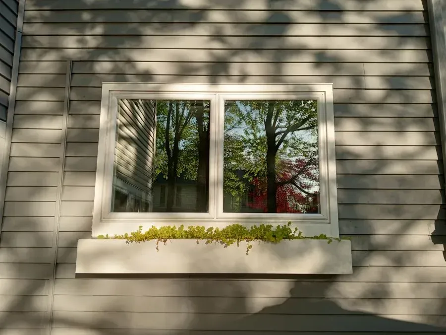 A window on the side of a house with a planter in it