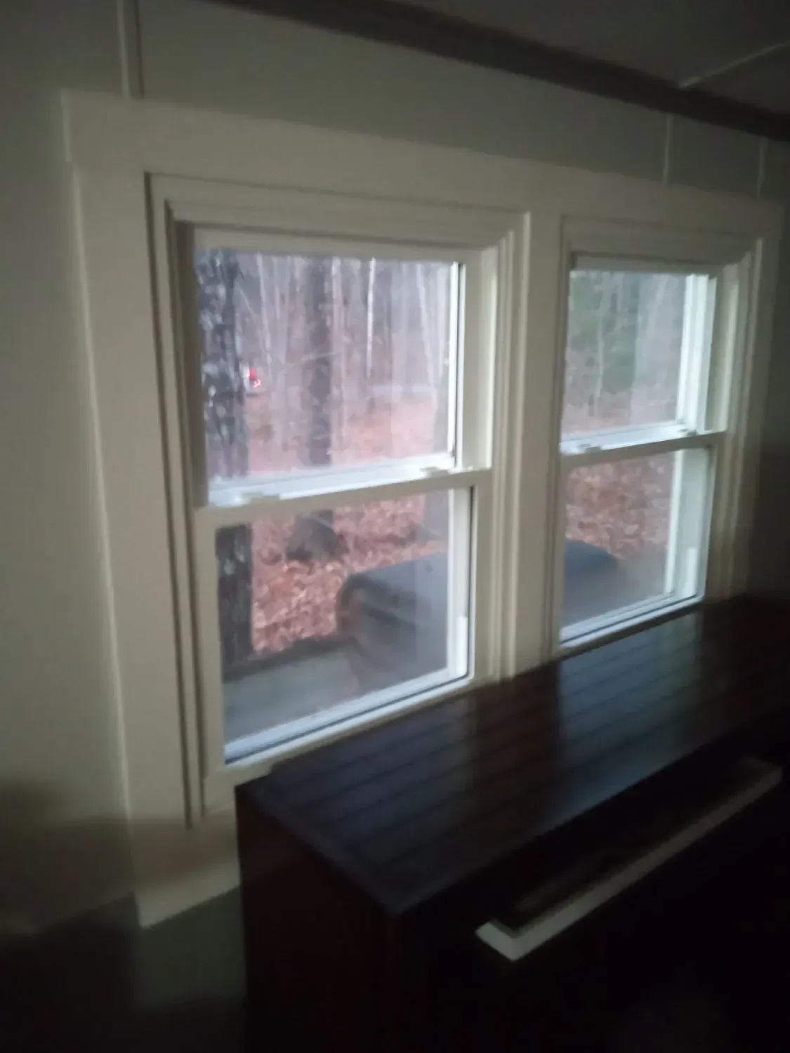 A room with two windows and a piano in front of them