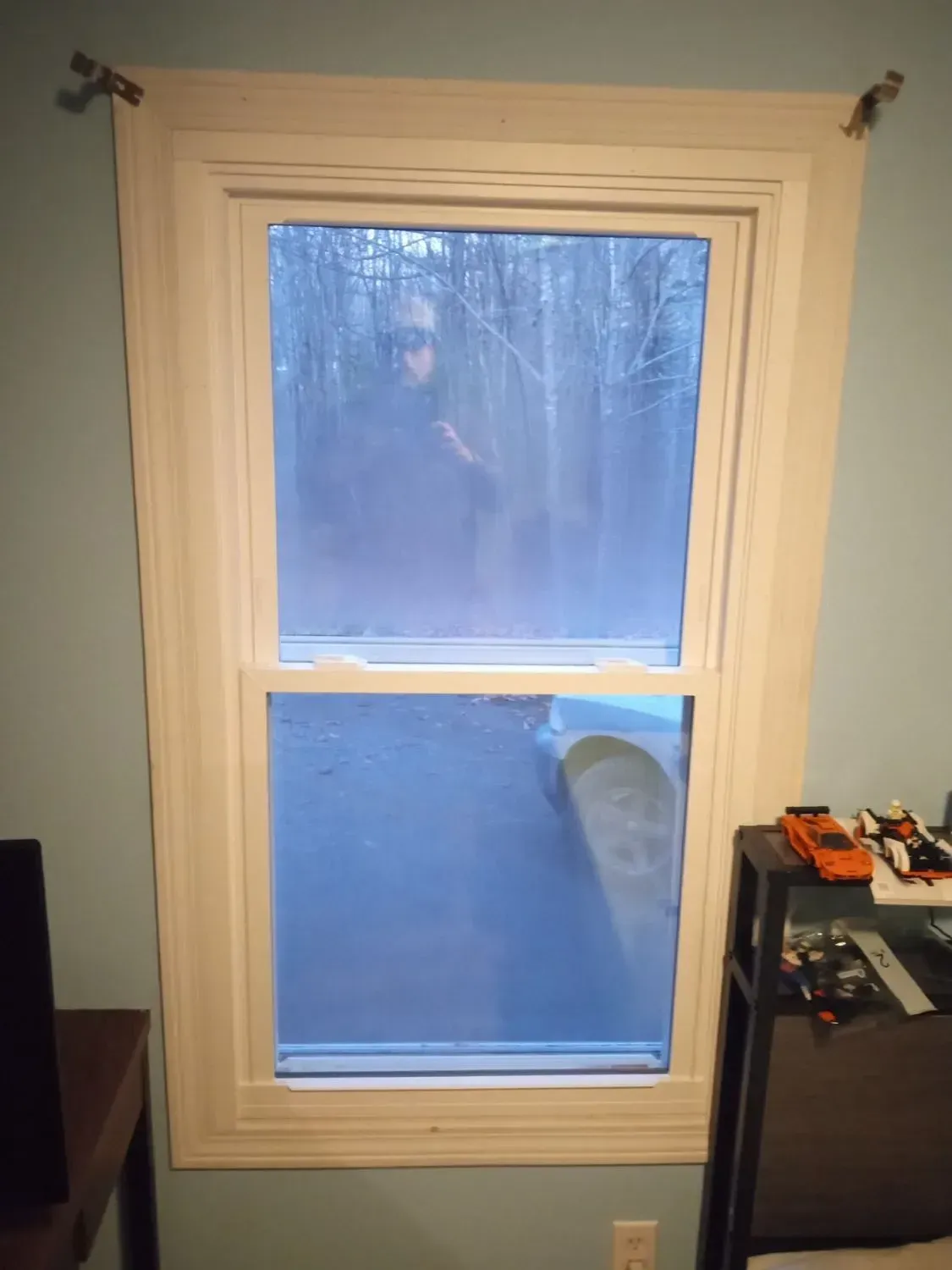 A person is standing in front of a window in a room.