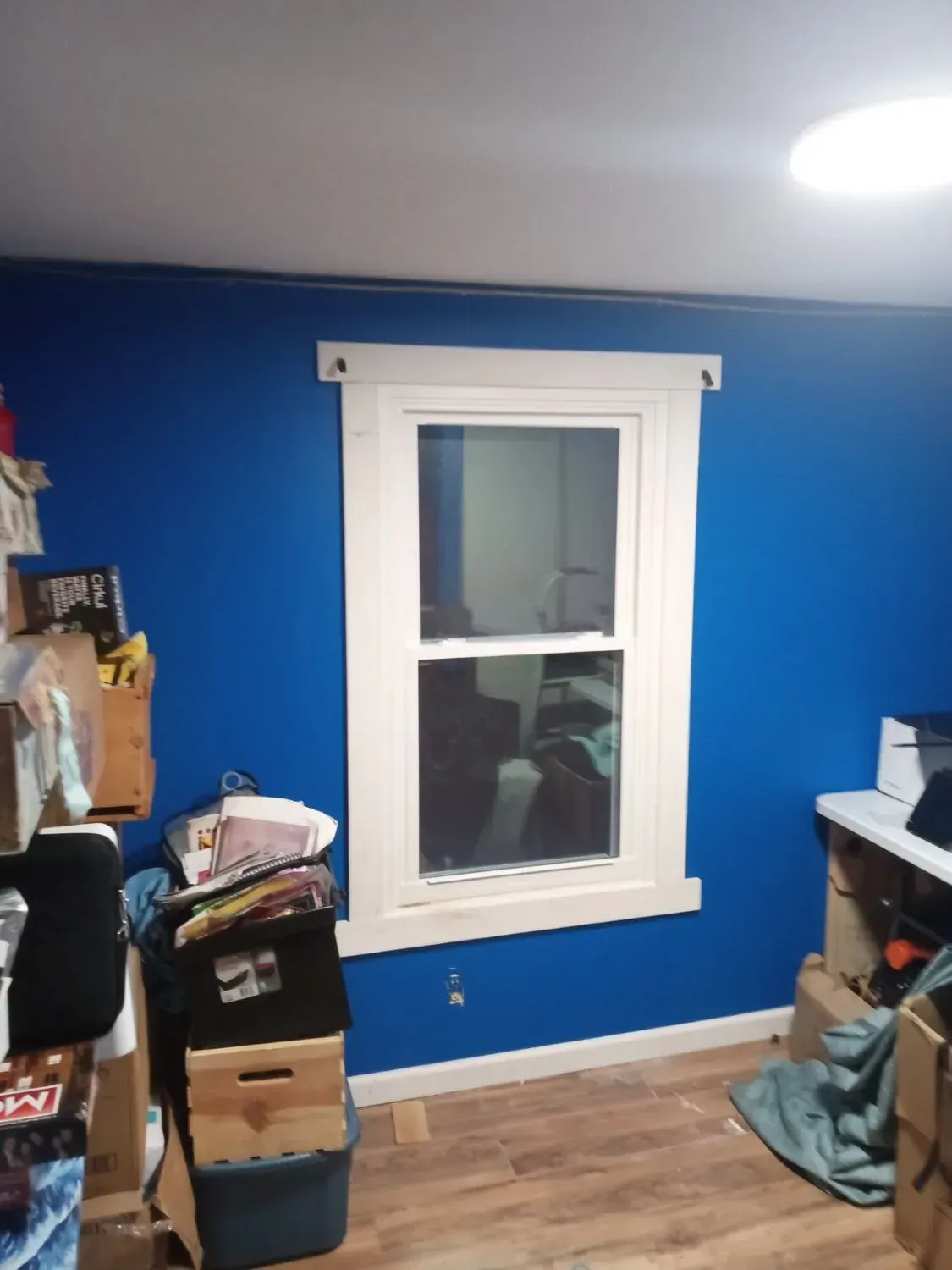 A room with blue walls and a window filled with boxes.