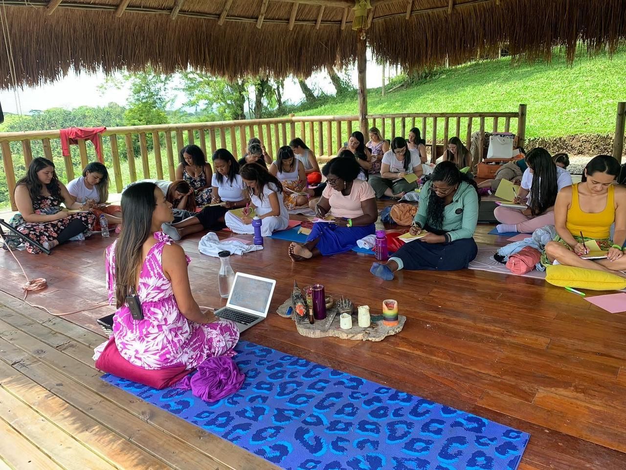 Grupo de personas que asisten a un taller al aire libre. Una mujer dirige la sesión utilizando un ordenador portátil.