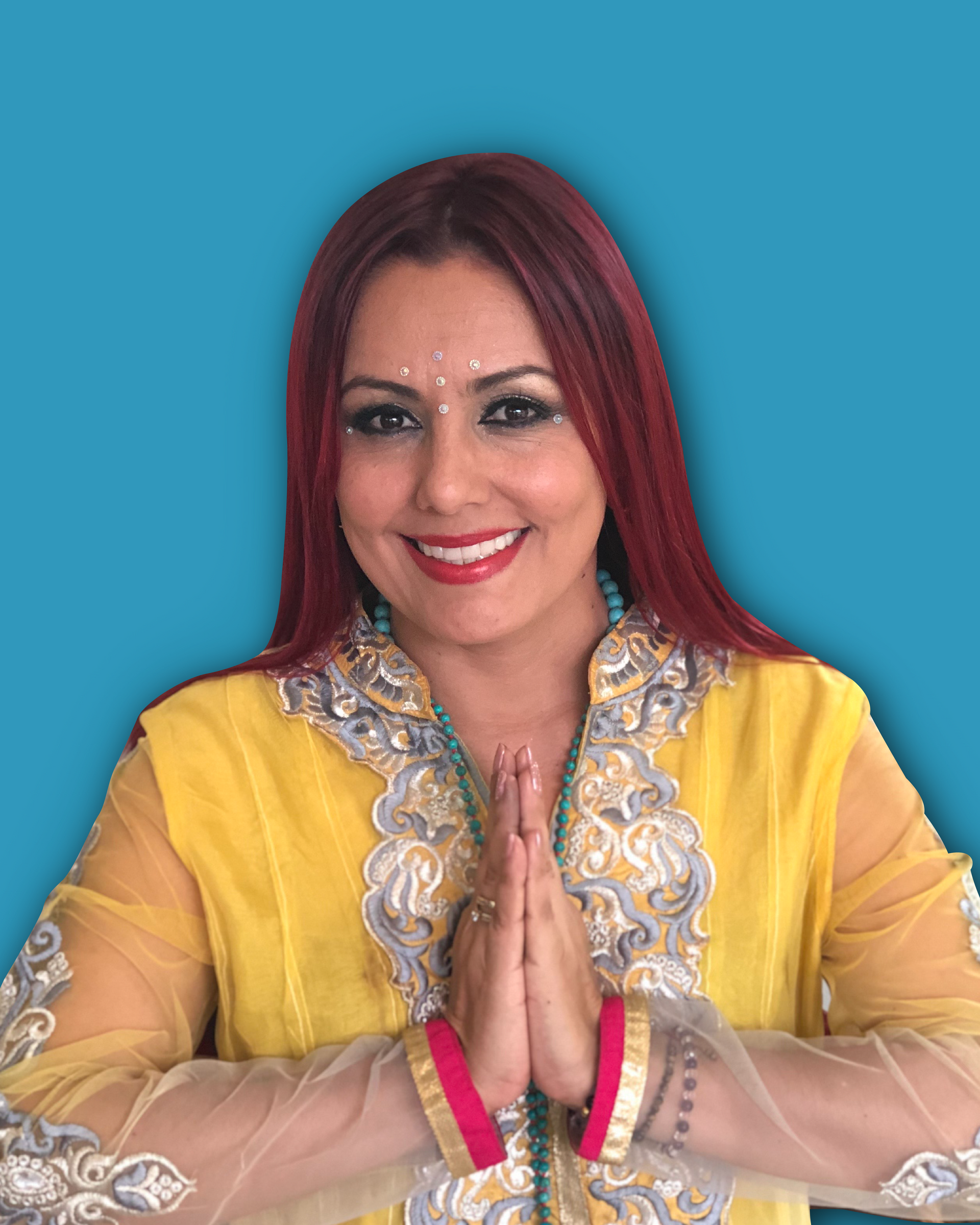 Mujer con ropa bordada en amarillo y azul, manos en posición de oración, sonriente, cabello rojo.