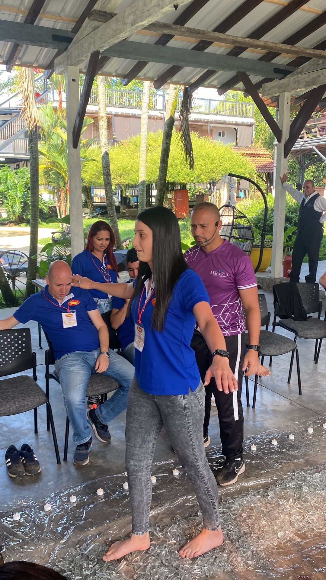 Grupo de personas en un área exterior techada. Una mujer baila mientras los demás la observan. Hay pelotas de espuma esparcidas por el suelo.