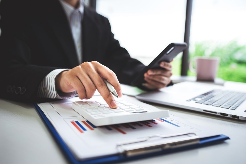 A Man is Using a Calculator While Holding a Cell Phone — Forsyths Accounting Services Pty Ltd in Mackay, QLD