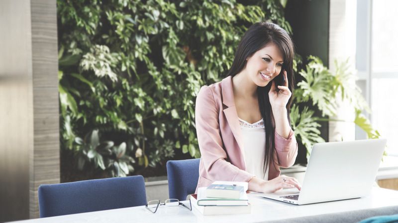 A Woman Using a Laptop Computer While Talking on a Cell Phone — Forsyths Accounting Services Pty Ltd in Mackay, QLD