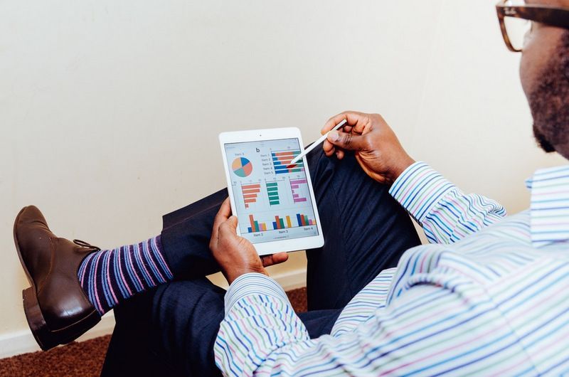 A Man is Sitting on the Floor Using a Tablet Computer — Forsyths Accounting Services Pty Ltd in Mackay, QLD