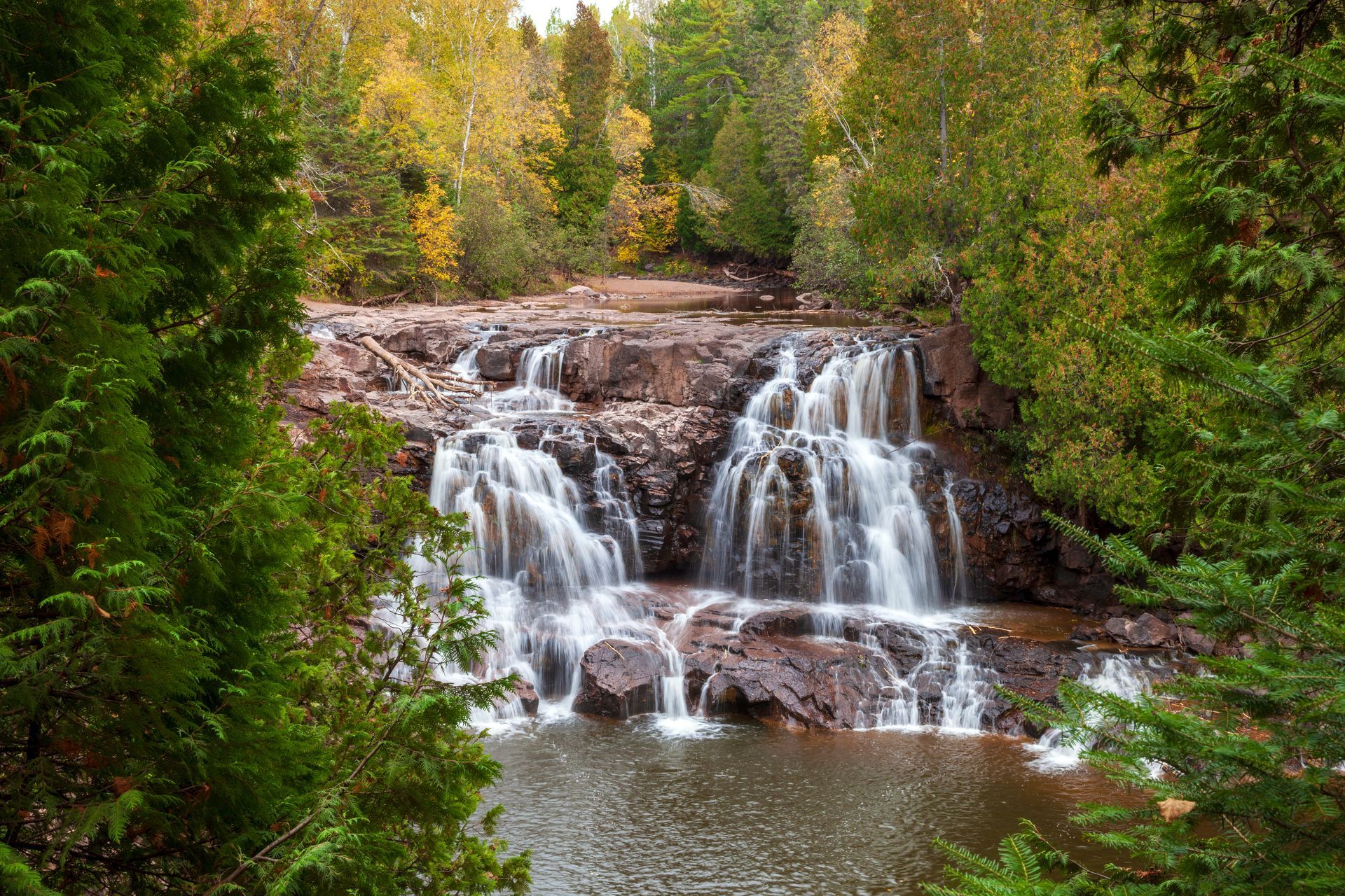 A waterfall is surrounded by trees in the middle of a forest.