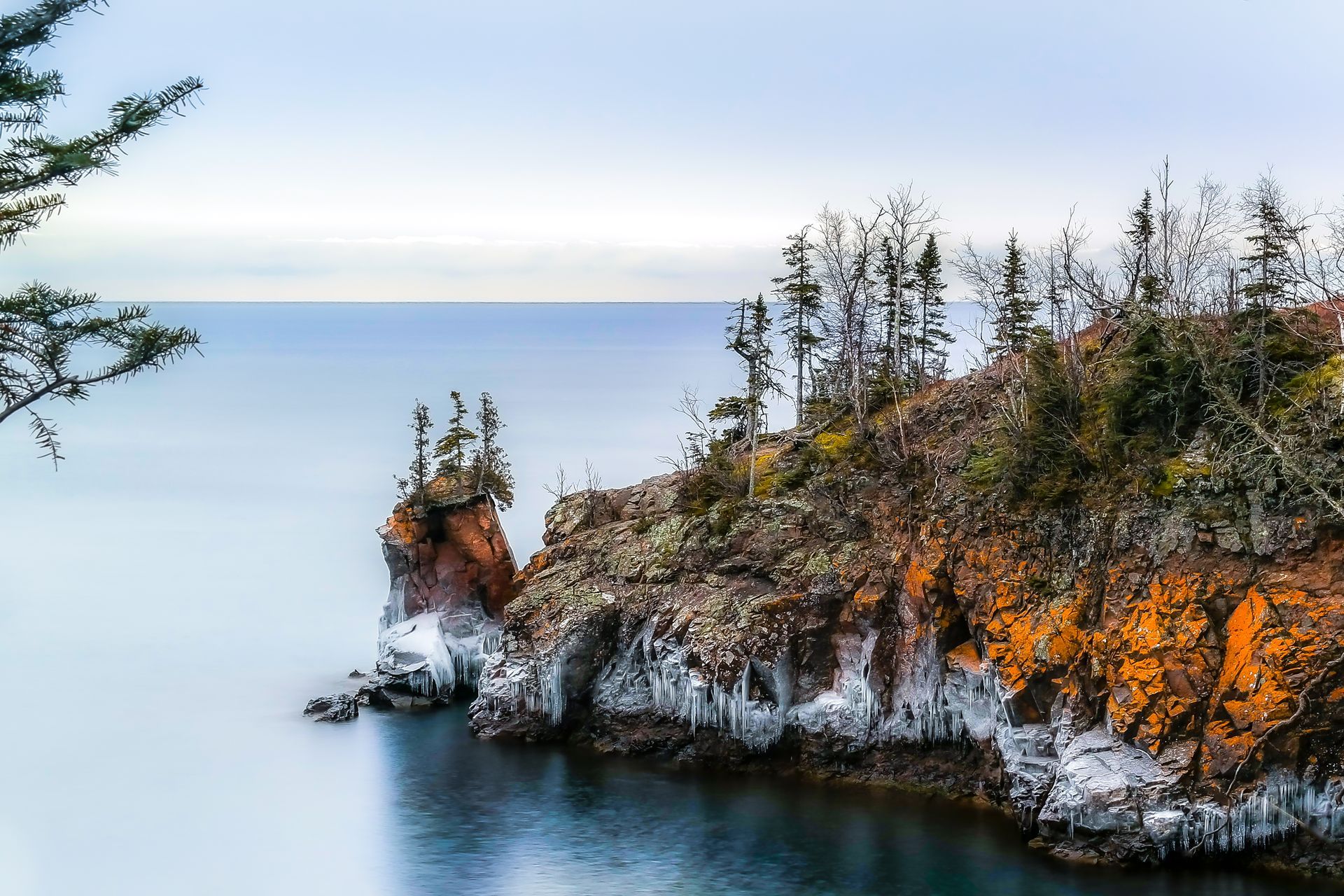 A cliff overlooking a body of water with trees on it.
