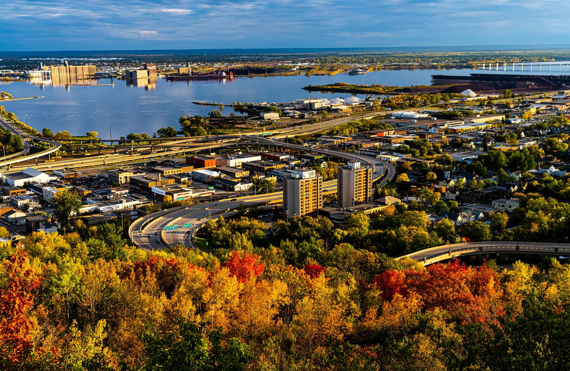 An aerial view of a city surrounded by trees and a body of water.