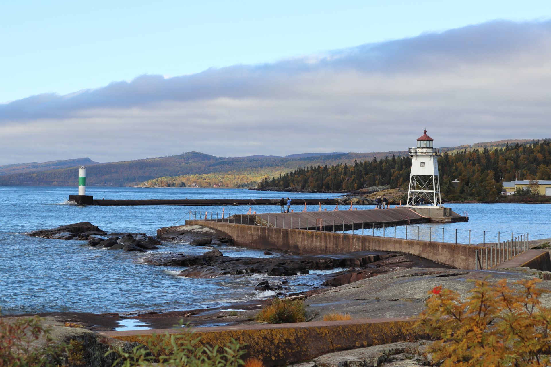 A lighthouse is sitting on top of a pier next to a body of water.