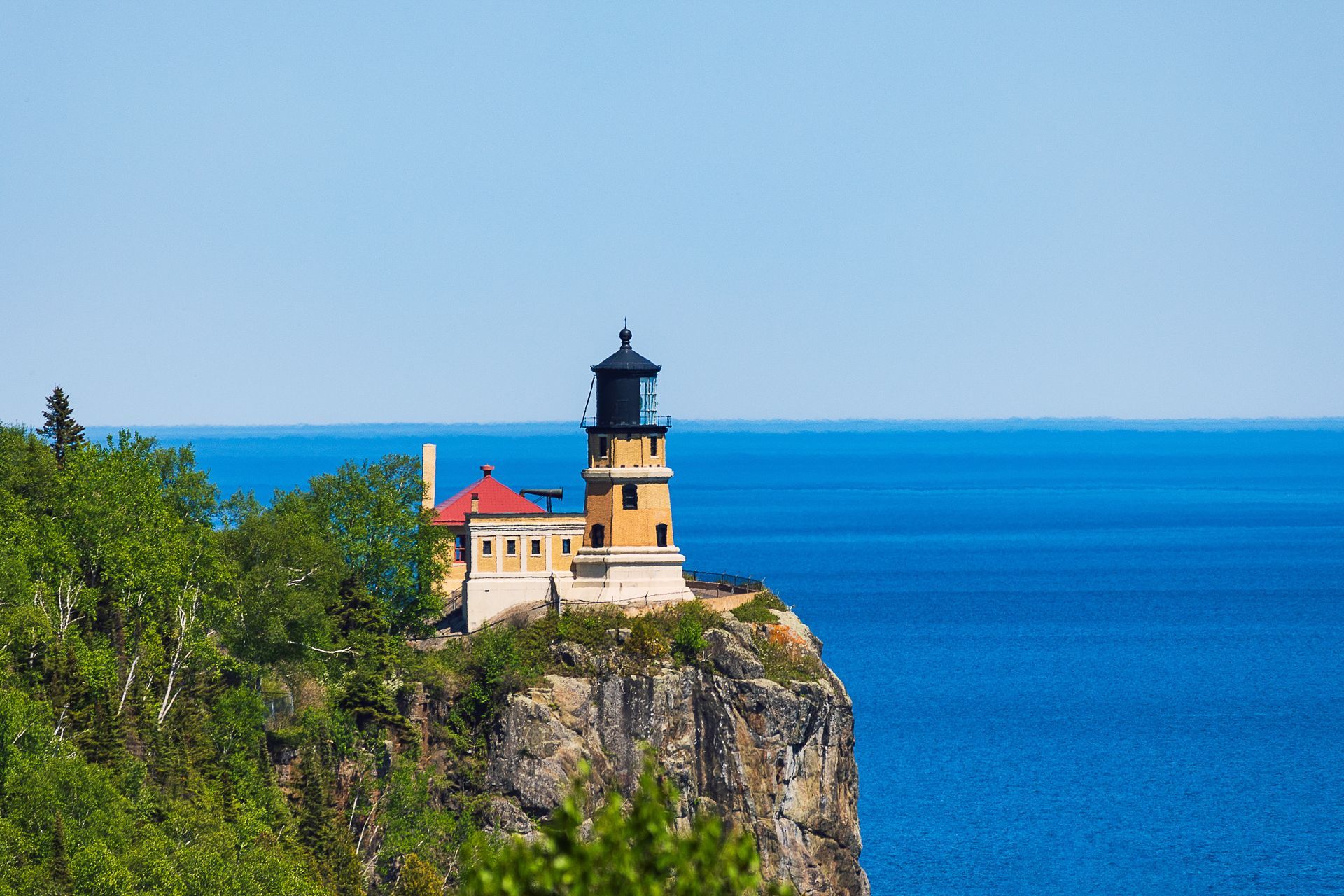 A lighthouse is sitting on top of a cliff overlooking the ocean.