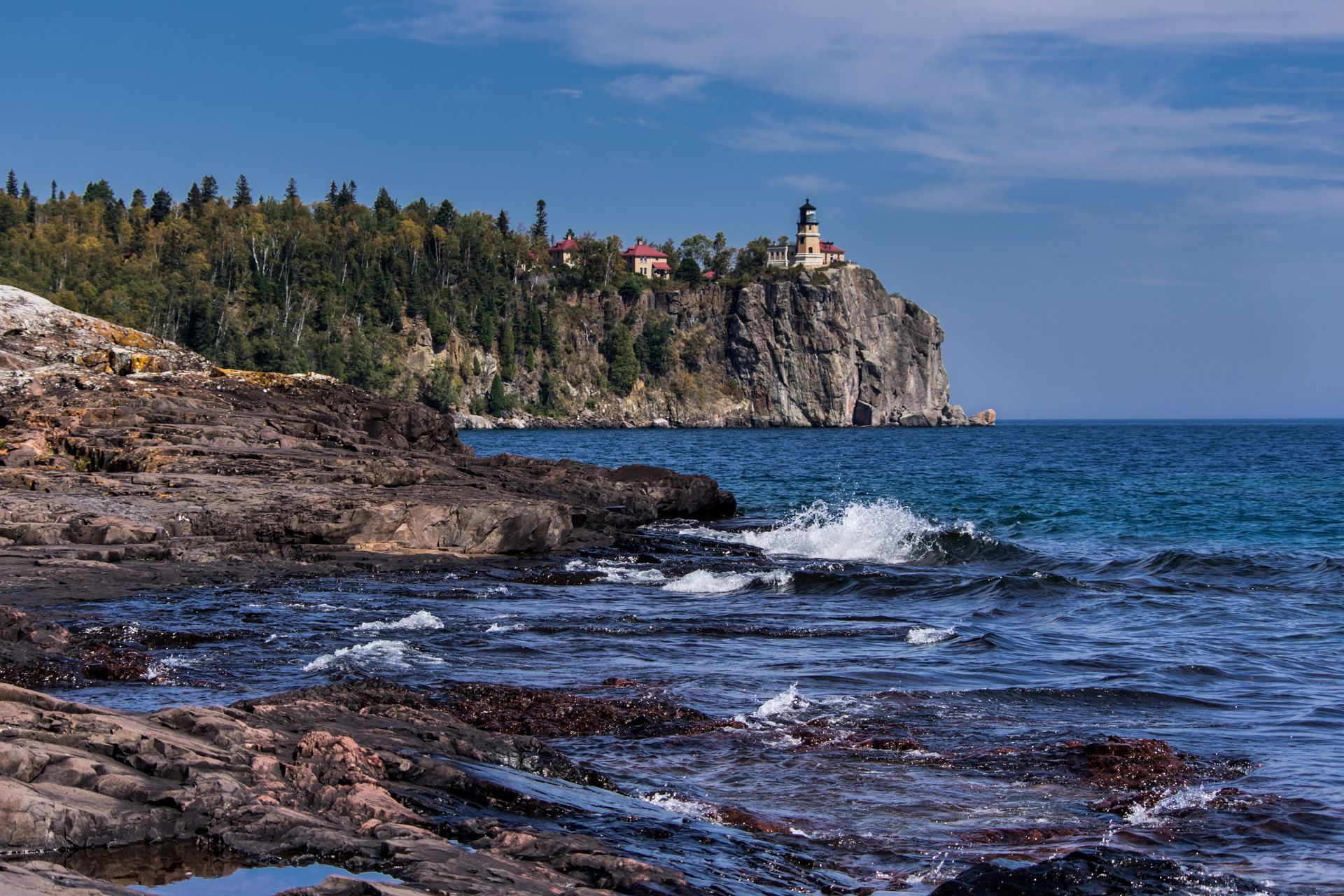 A lighthouse on top of a rocky cliff overlooking the ocean.